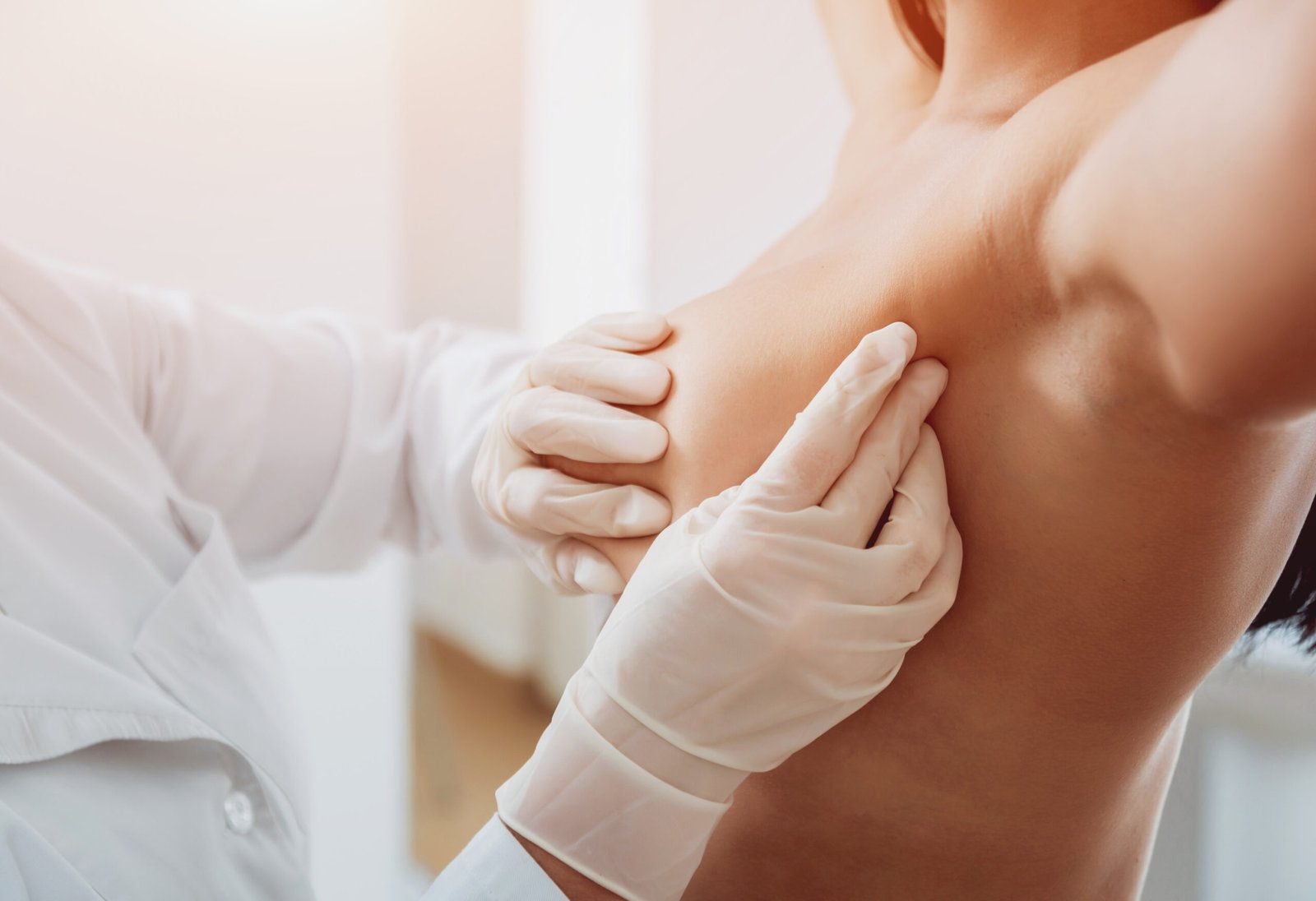 Doctor get examining breast of young woman. Consultation with gynecologist.